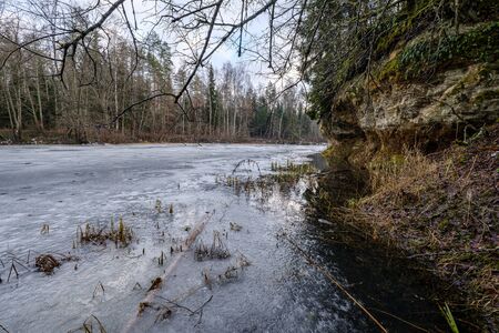 sandstone cliffs in Latvia near river Gauja with ice on water. winter landscapeの写真素材