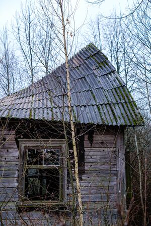 old abandoned house exterior with broken furniture and empty windows in autumnの写真素材