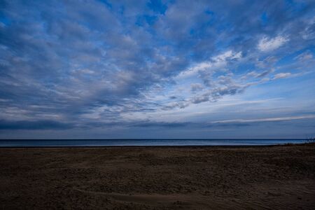 empty sea beach in autumn with some bushes and dry grass. water in perspectiveの写真素材
