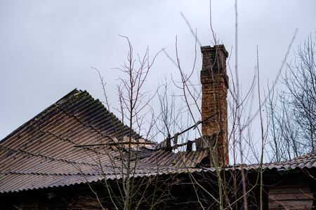 old abandoned house exterior with broken furniture and empty windows in autumnの写真素材