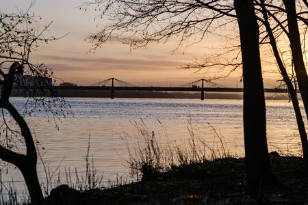 sunset over the city with dark tree trunk silhouettes in front. autumnの写真素材