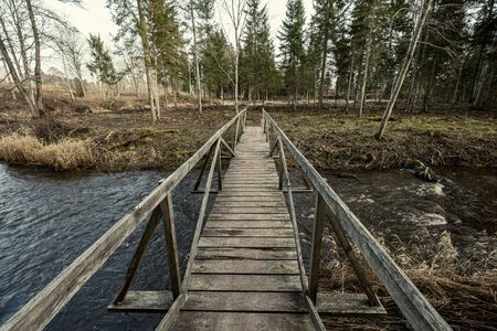 old wooden bridge over the river in forestの写真素材