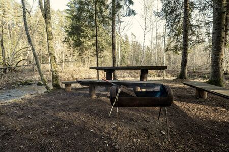 resting camping place in the woods with benches and trail in late autumn in Latviaの写真素材