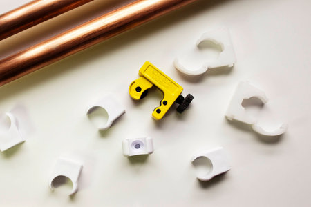 Plumber assembles copper pipes, cutter and plastic fixings on work benchの写真素材