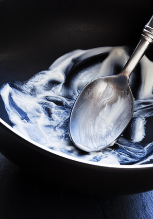 Black bowl that shows yoghurt that's been eaten and the remains left withinの写真素材