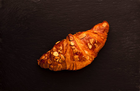 Single almond croissant on black slate baseの写真素材