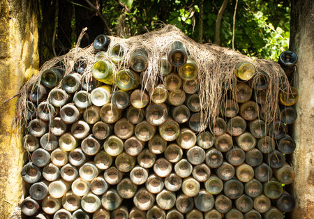 wall of stacked glass bottles abandoned in a gardenの写真素材