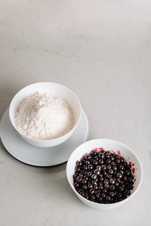 Flour and black currant Ingredients for baking. Top view, close-up. Black currant and sugar in a...