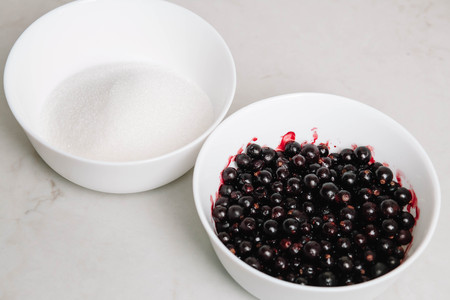 Black currant jam with sugar. Berries background. Top view, close-up. Black currant and sugar in a bowls in whiteの写真素材