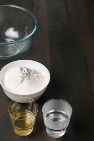 Baking wooden background with ingredients for pizza dough. Baking utensils on dark rustic table, top view. Copy spaceの写真素材
