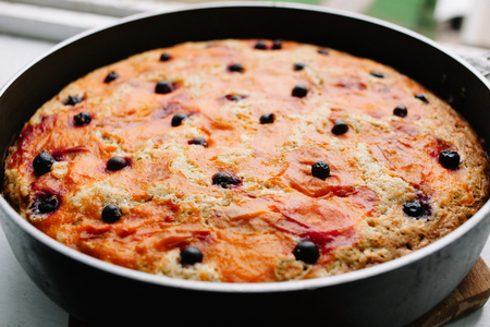 Freshly baked delicious blackcurrant apple pie Charlotte cools down in a culinary form on a wooden boardの写真素材