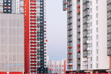The facade of a high-rise building with red white and gray stripes. Multi-storey building against the blue sky. Background to illustrate the articleの写真素材