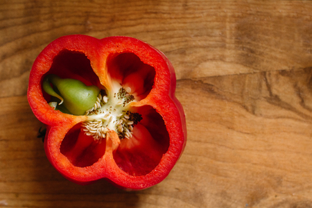 Fresh sweet red pepper cut in half with a growth inside on old wooden backgroundの写真素材