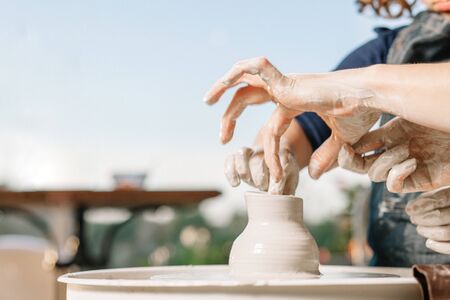 Art therapy. Womens hands make a pot of clay on a potters wheel. Workshop on potteryの写真素材