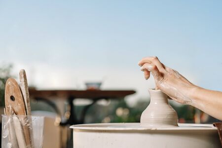 Art therapy. Womens hands make a pot of clay on a potters wheel. Workshop on potteryの写真素材