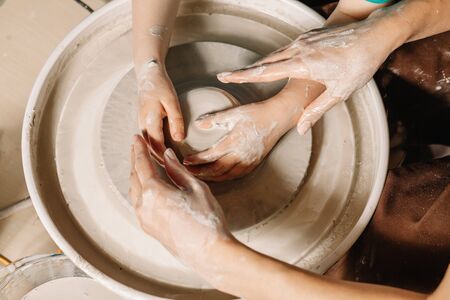 Professions Ideas. Woman potter teaching the art of pot making. Child working on potters wheel making clay objects in pottery workshop.の写真素材