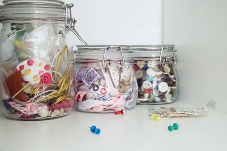 Colored ribbons and colorful buttons in glass jars for creating artistic hobbiesの写真素材