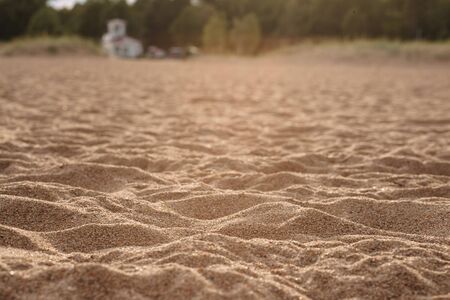 The sand on the beach in the rays of the warm sunset sun hills cast cool shadows. A large fraction of sand close-up with a blurred background.の写真素材