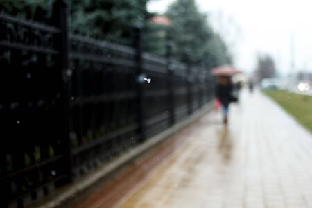 Abstract silhouette of a woman under an umbrella, city traffic, city streets in winter with snowflakesの写真素材