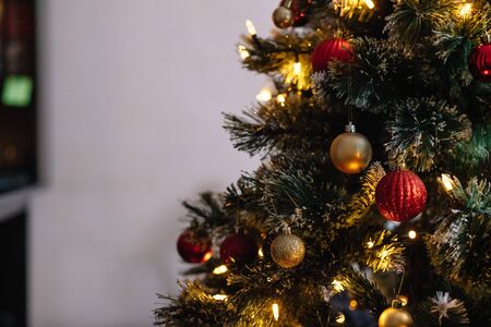 Red and golden balls on an artificial Christmas tree with lights and bokeh with copy spaceの写真素材