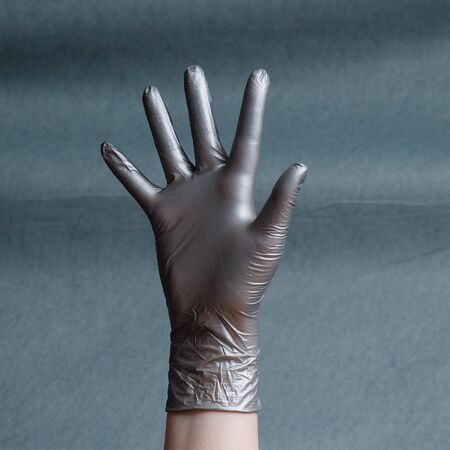 Hand in silver nitrile glove on a gray background with a gradient. Square aspect ratioの写真素材
