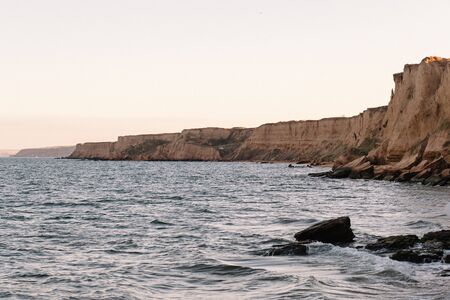 Crimea, Russia. The picturesque landscape of the Black Sea coast, known as Eltigen. Sandy seashore and rocky cliffs in the evening sunlight.の写真素材