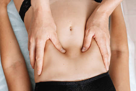 Top view of hands massaging the female abdomen. Therapist, osteopath applying pressure on the...