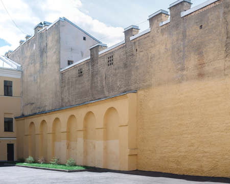 A beige wall with elements in the form of arches in the courtyard of the house. On top of the wall, the battlements.の写真素材