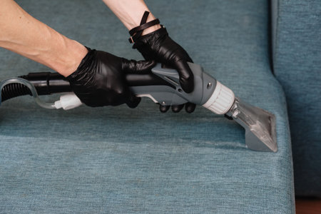 Men use a vacuum cleaner to clean the sofaの写真素材