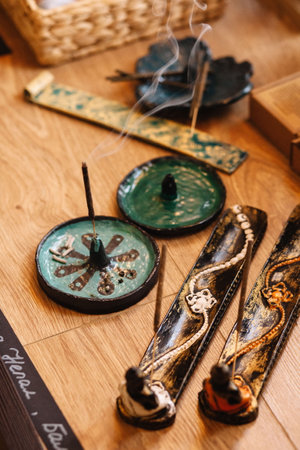 Steaming incense stick in a round ceramic holder on a tableの写真素材