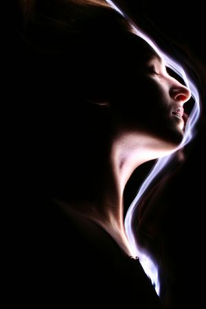 It is sideview of young white girl. It is maked with the light line on the black background.の写真素材