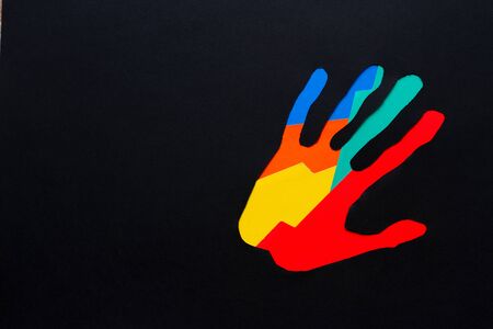 Paper collage of a colourful hand on a black background.の写真素材