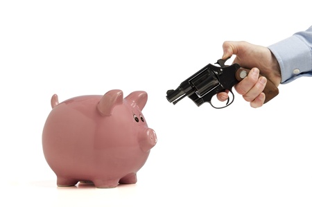 Close-up of a piggy bank being robbed by an armed man, isolated on whiteの写真素材