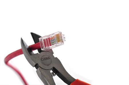 Wire cutters with bright orange handles poised to snip the end off of a cat 5 computer networking cable; China stamp on the cutters symbolizes the countryの写真素材