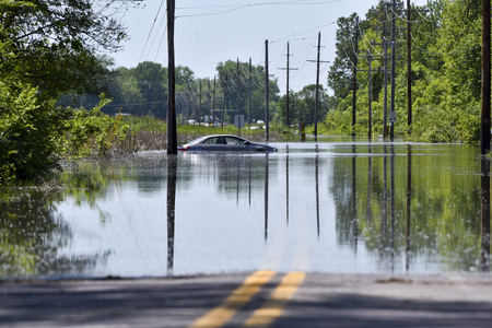A car sits stranded after getting stuck on a flooded roadの写真素材