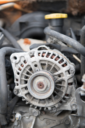 An old alterntor with a little visible rust and no belt is still mounted inside an old car engineの写真素材