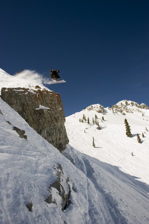 A Skier launches straight off a cliff with mountains in backgroundの写真素材