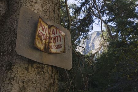 A private property no trespassing sign, on pine tree, with mountain peak in the background.の写真素材