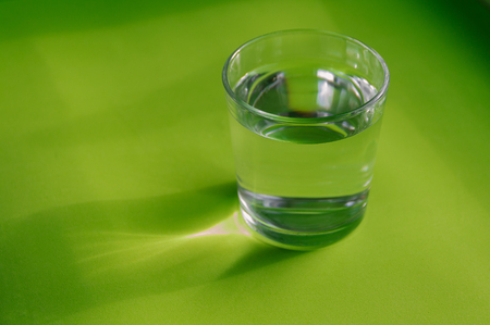 A glass of purified water on a bright green background.の写真素材