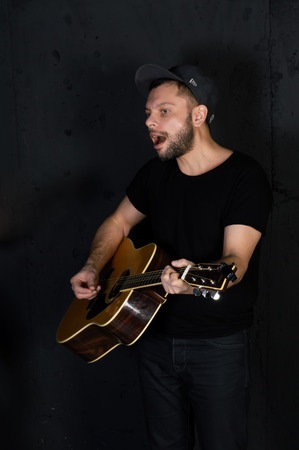 NOVOCHERKASSK. RUSSIA. FEBRUARY 1, 2017. A man plays the guitar and sings a song. Black background.のeditorial素材