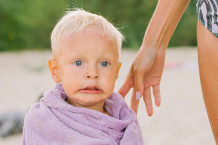 Little cute girl with wet hair in a pink towel on the beach.の写真素材