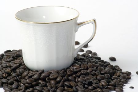 A coffee cup sitting in a pile of coffee beansの写真素材