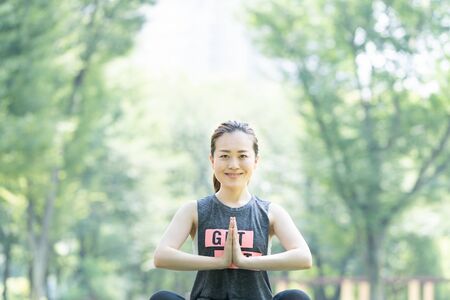 A woman doing yoga stretches in the parkの写真素材