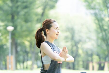 A woman doing yoga stretches in the parkの写真素材