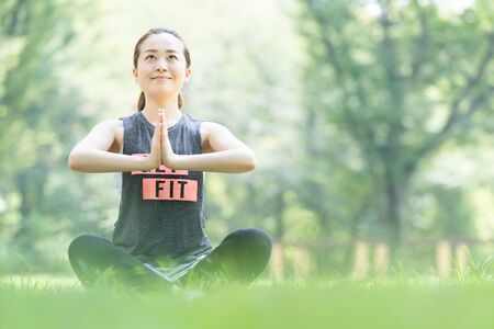A woman doing yoga stretches in the parkの写真素材