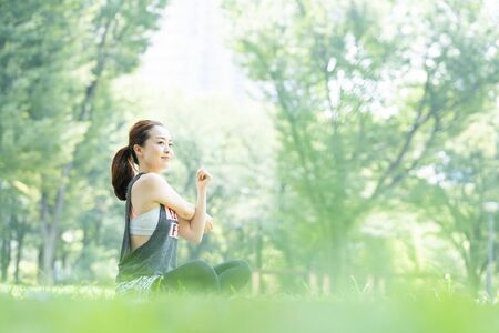 A woman doing yoga stretches in the parkの写真素材