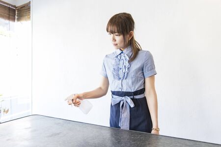Young Asian woman spraying disinfectant spray to the table in house