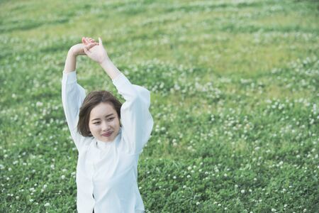 Asian young woman showing a relaxed expression on the meadowの写真素材