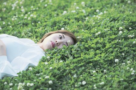 Asian young woman showing a relaxed expression on the meadowの写真素材