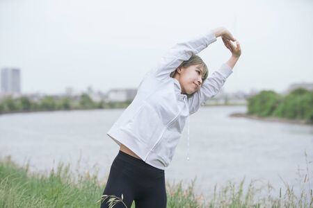 Asian young woman doing stretching exercise in urban green space